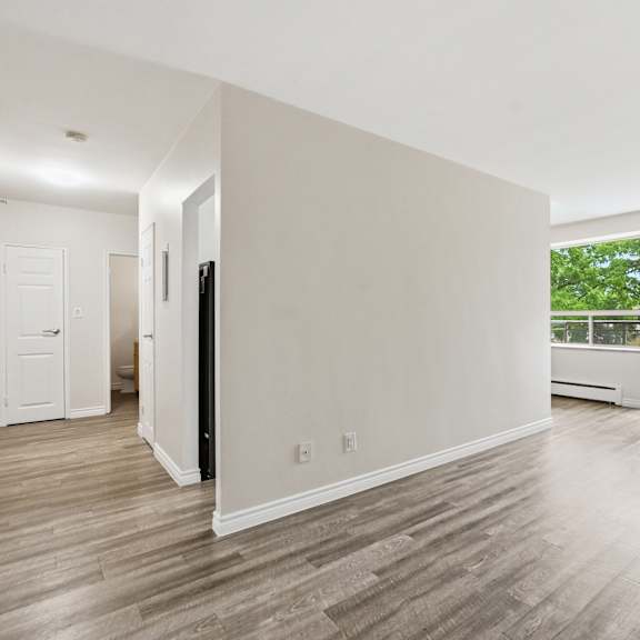 a spacious room with wooden flooring and a view of trees through the window.