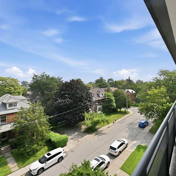 a view from a balcony overlooking a street with cars and houses.