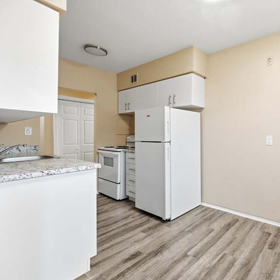 a kitchen with white appliances and wooden floors.