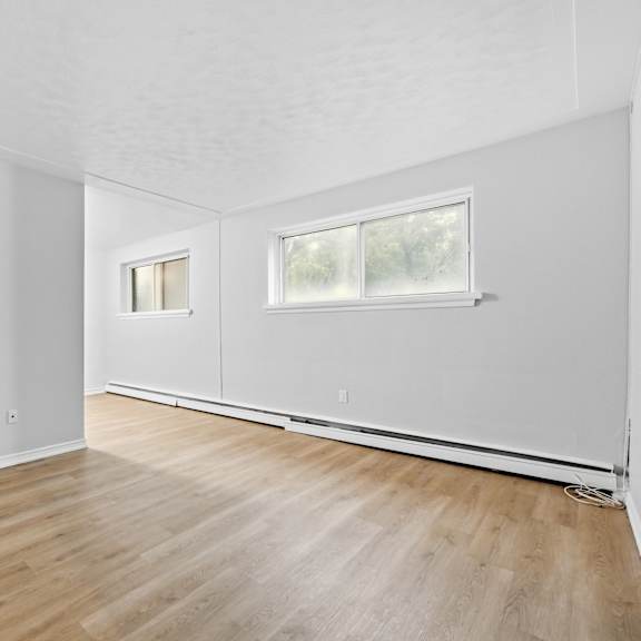 a room with wooden flooring and two windows.