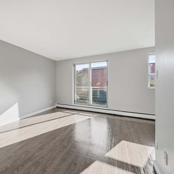 a room with wooden flooring and a window showing a view of a building outside.