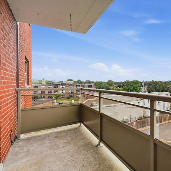 a balcony with a view of a parking lot and trees.