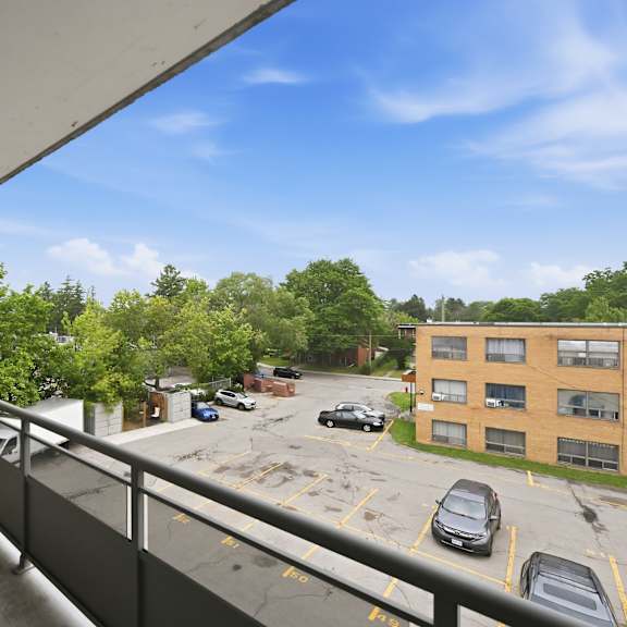a balcony overlooks a parking lot and a building.