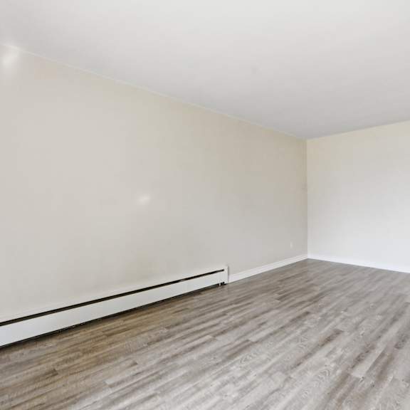 empty room with wooden flooring and white walls.