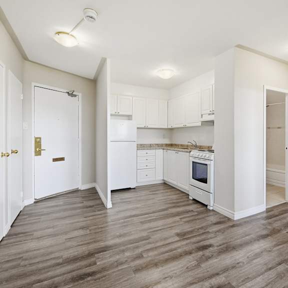 a kitchen with white cabinets and a wooden floor.