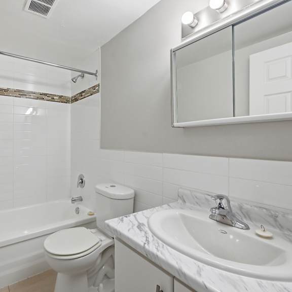 a white bathroom with a toilet, sink, and bathtub.