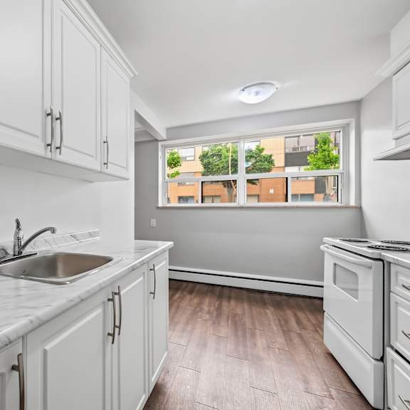 a kitchen with white cabinets and a marble countertop.