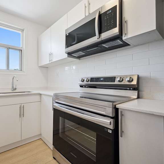a kitchen with white cabinets and black appliances.