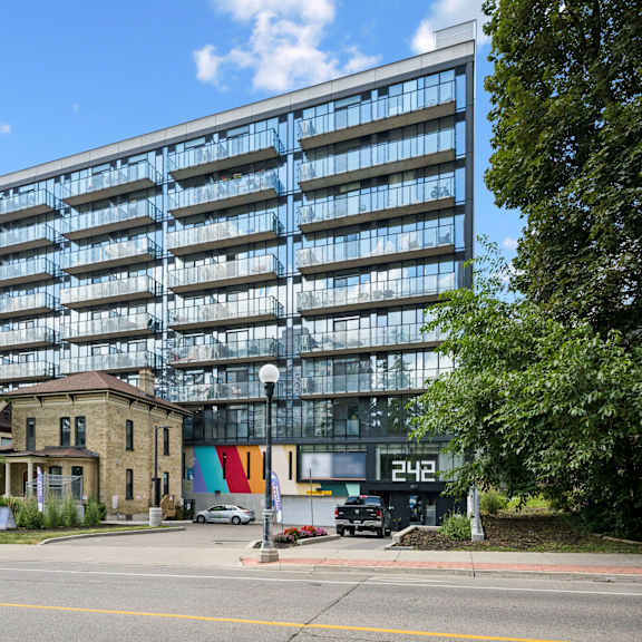 a modern glass building is situated next to a tree and a house.