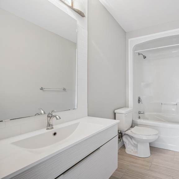 a white bathroom with a sink, toilet, and shower.