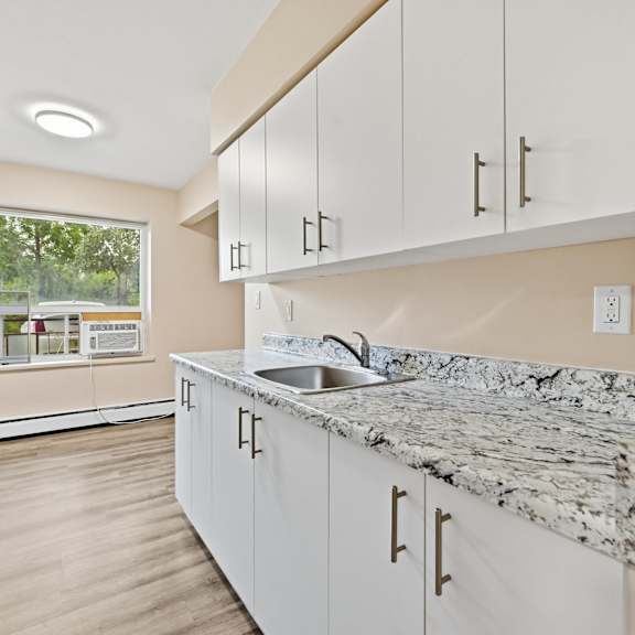 a kitchen with a marble countertop and white cabinets.