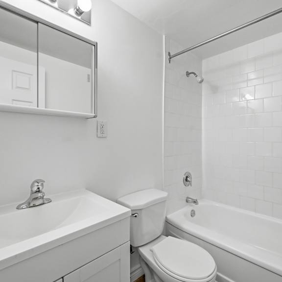 a white bathroom with a sink, toilet, and bathtub.