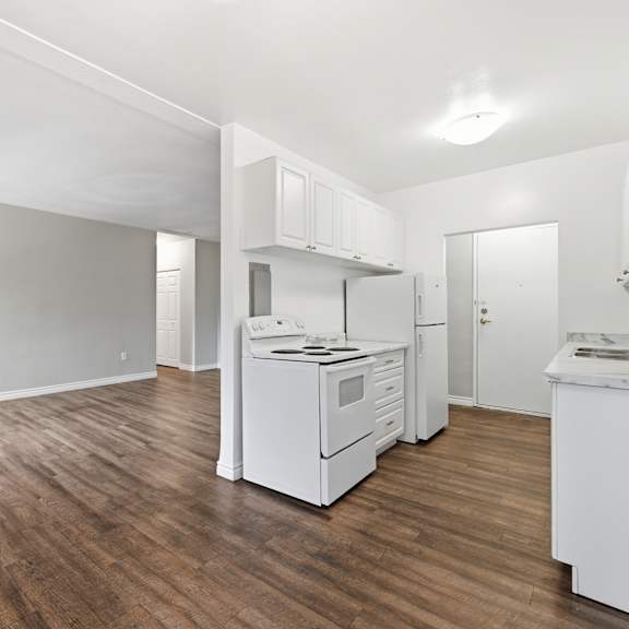 a kitchen with white appliances and wooden floors.