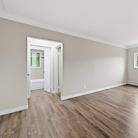 a room with wooden floors and a window showing a view of a building.