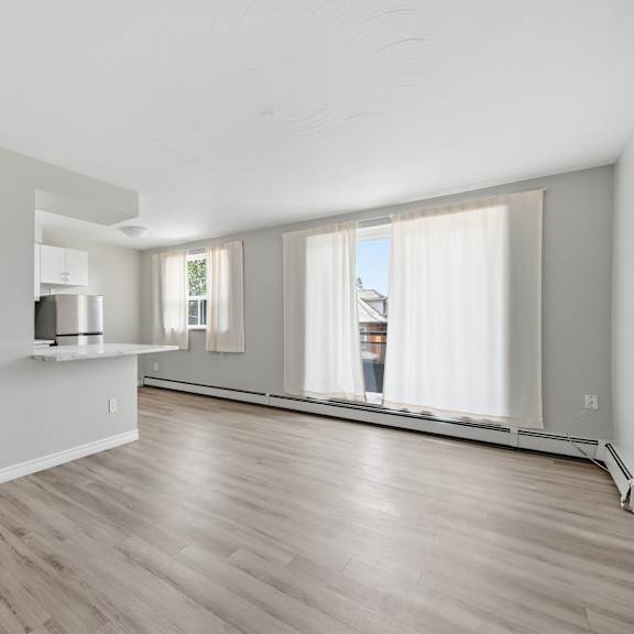 a spacious living room with wooden flooring and white walls.