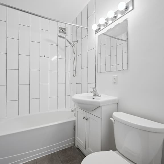 a white bathroom with a white tub, sink, and toilet.