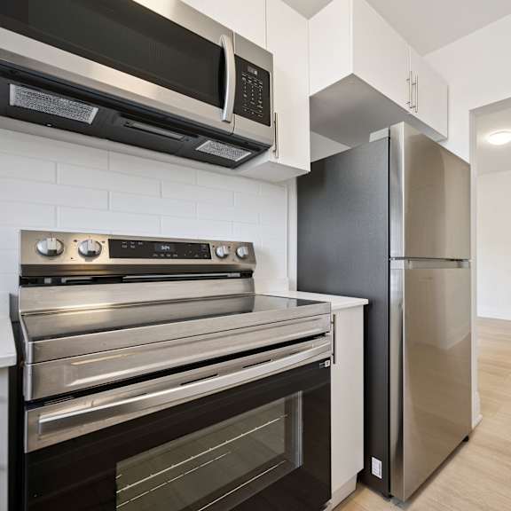 a kitchen with a black microwave, stove, and refrigerator.