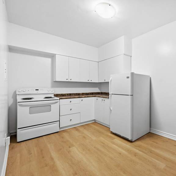 a kitchen with white appliances and wooden floors.