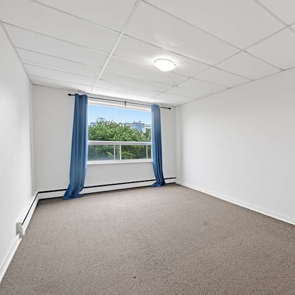 a room with a carpeted floor and a window with blue curtains.