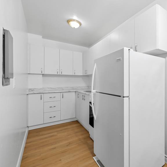 a white kitchen with a refrigerator, oven, and cabinets.