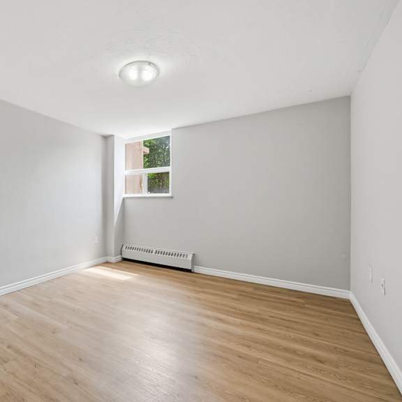 a room with wooden flooring and a window with a view of a building outside.