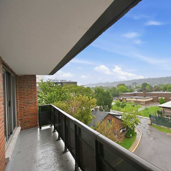 a balcony overlooks a wet street and buildings.