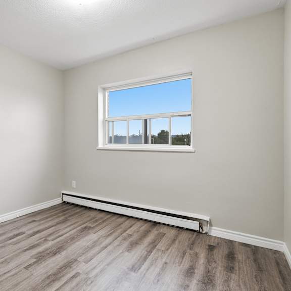 a room with a window and wooden flooring.