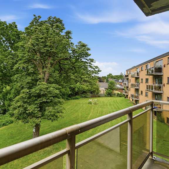 a balcony overlooks a green lawn and a body of water.