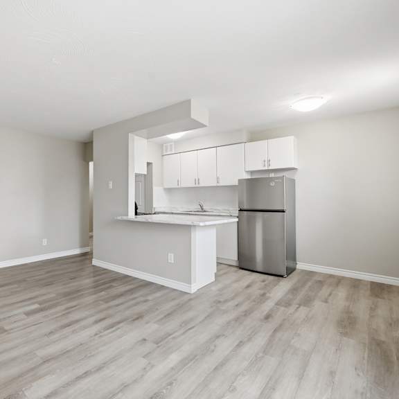 a kitchen area with a refrigerator, sink, and cabinets.