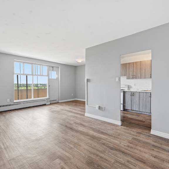 a spacious room with wooden flooring and a large window.