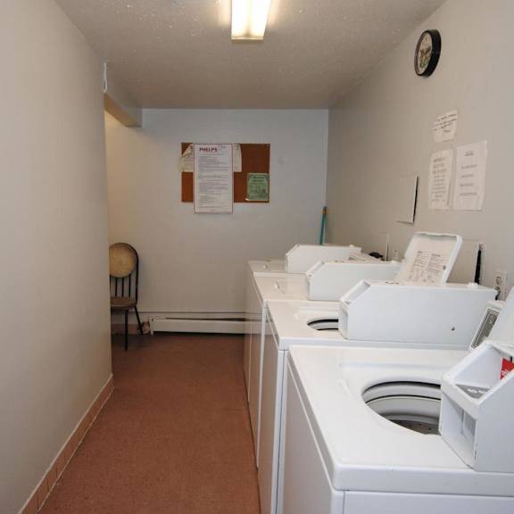 a white washing machine sits in a small room with a brown carpet.