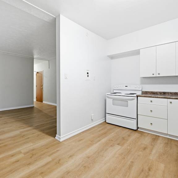 a white kitchen with a wooden floor and white appliances.