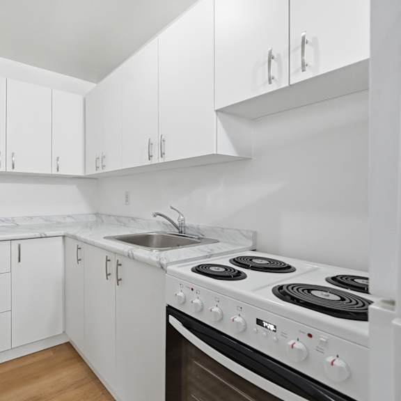 a white kitchen with a stove and cabinets.