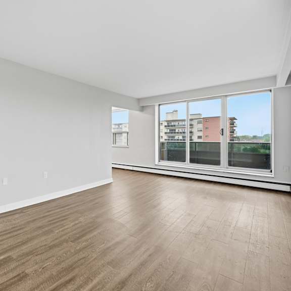 a spacious room with wooden flooring and large windows.