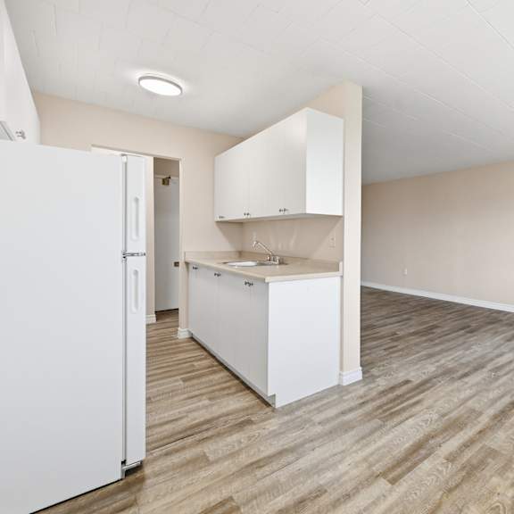 a kitchen with a white fridge and wooden floors.