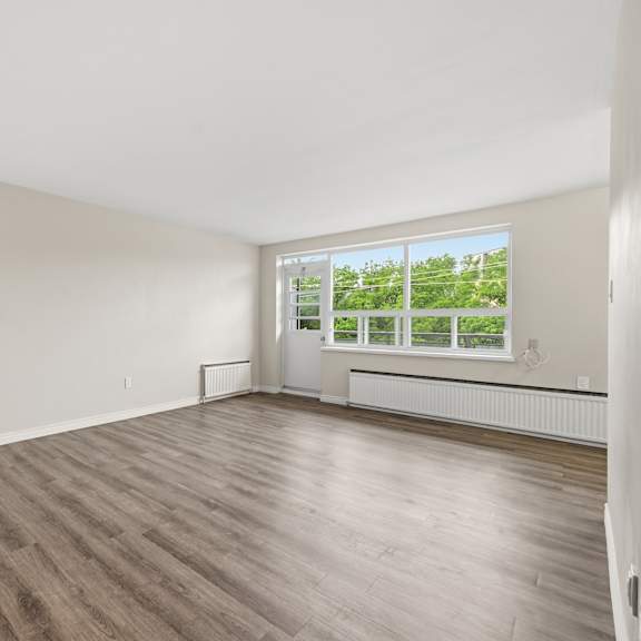 a room with wooden flooring and a window overlooking a green landscape.