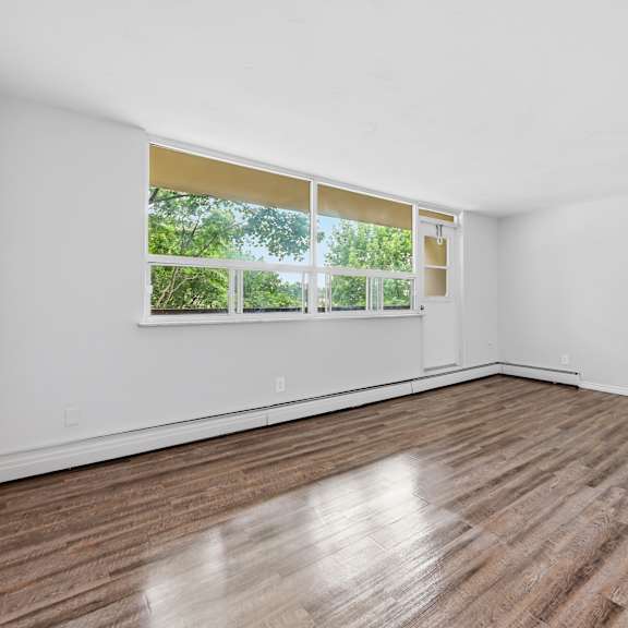 a room with wooden flooring and a window with blinds.