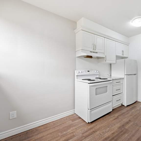 a white kitchen with wood flooring and white appliances.