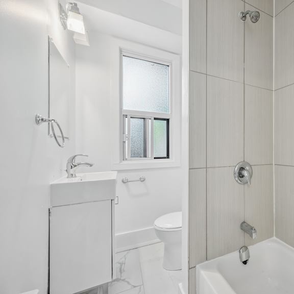 a white bathroom with a tub, toilet, and sink.