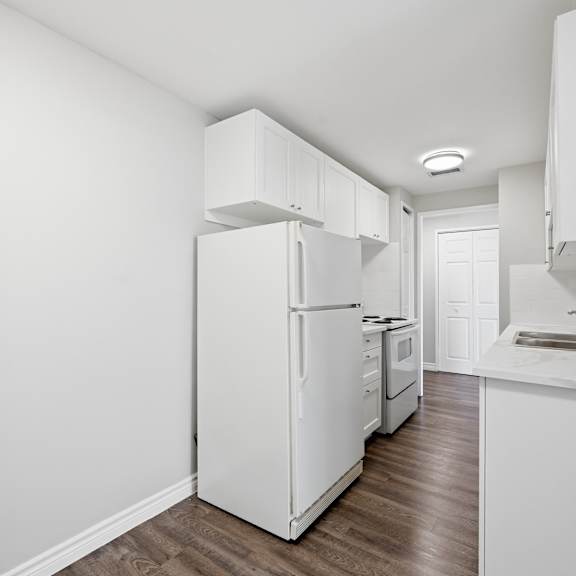 a white refrigerator in a kitchen with wooden floors.