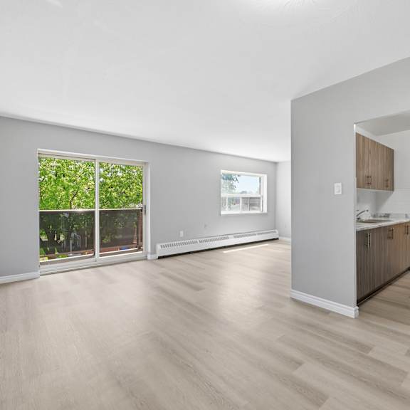 a spacious living room with a kitchen area in the background.