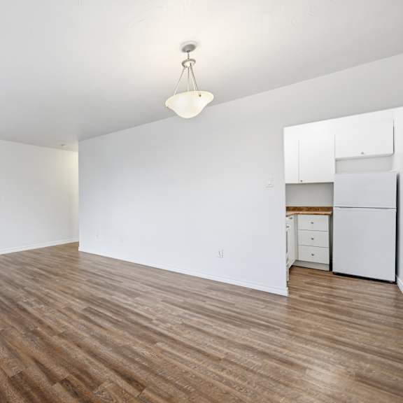 a room with wooden flooring and a kitchenette in the corner.