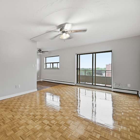 a room with a ceiling fan and wooden flooring.