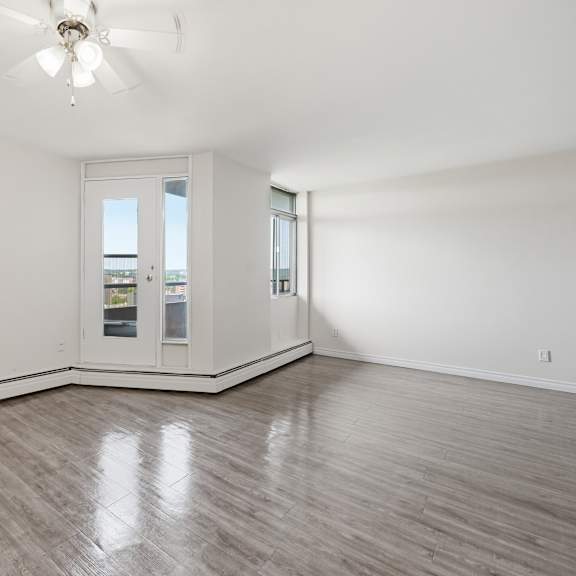 a room with a ceiling fan and a window overlooking a balcony.
