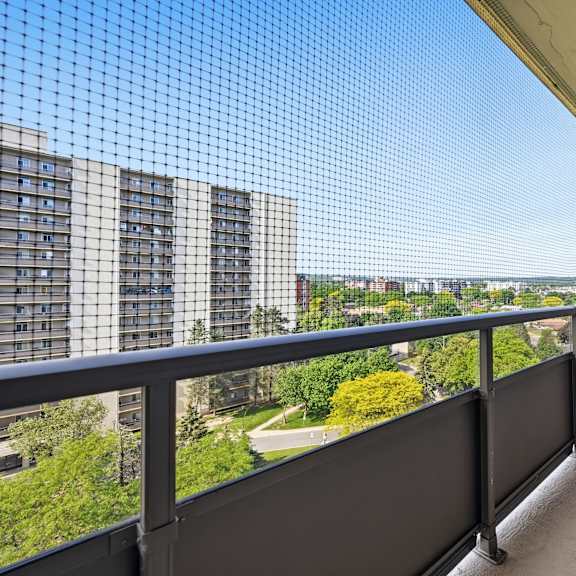 a balcony with a metal railing and a mesh screen overlooking a cityscape.