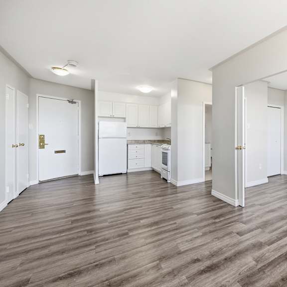 a spacious room with wooden flooring and white walls.