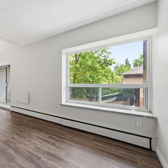 a room with a large window and wooden flooring.