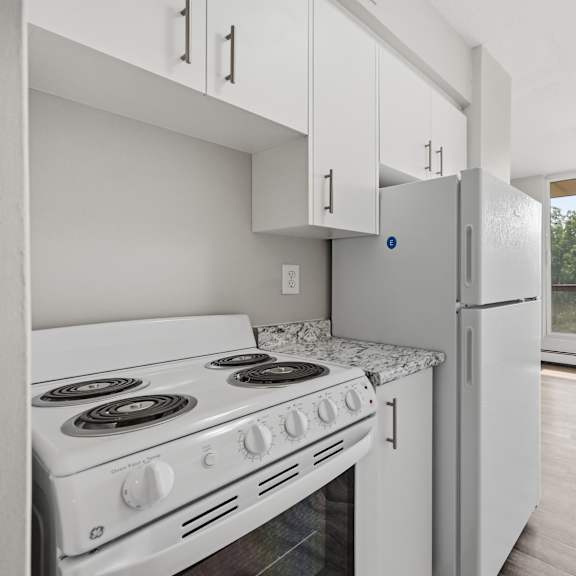 a white kitchen with a stove and refrigerator.