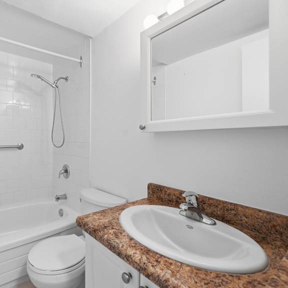 a white bathroom with a marble countertop and a white toilet.