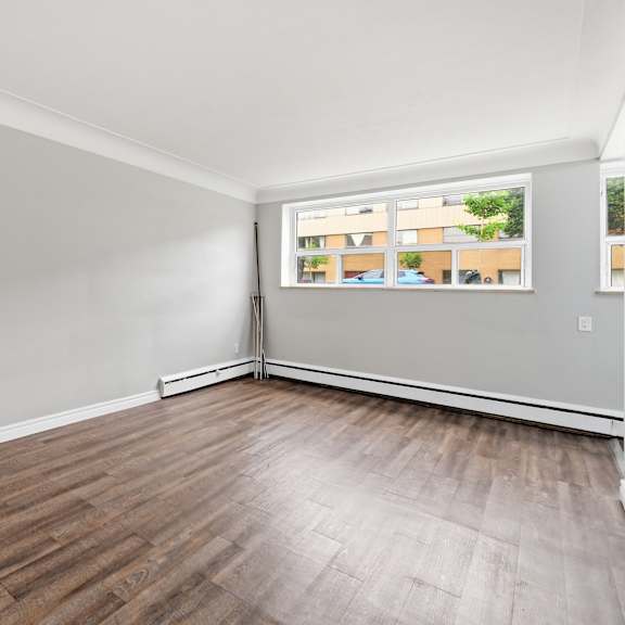 a room with wooden flooring and a window showing a view of a building.